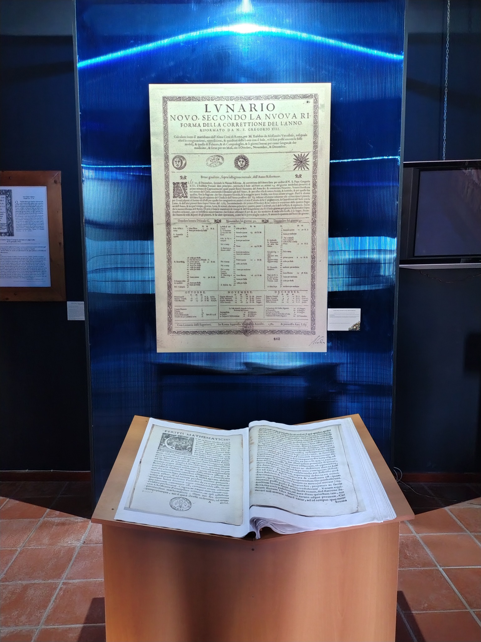 Display showing a Lunario sheet above an open historical book in the Luigi Lilio Museum